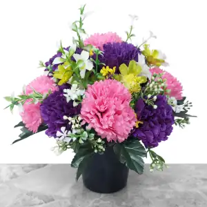 Artificial pink & purple carnations, and green cosmos, with gyp and greenery in a full black plastic grave flower pot.