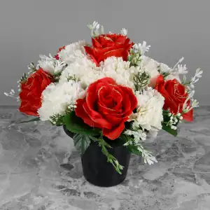 Artificial glittery red roses and ivory carnations with gyp and greenery in a full black plastic grave flower pot.