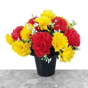 Artificial red & yellow carnations, with gyp and greenery in a full black plastic grave flower pot.