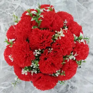Artificial red carnations with gyp and greenery in a full black plastic grave flower pot.