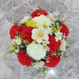 Artificial white cosmos, red & white carnations, and green cosmos, with gyp and greenery in a full black plastic grave flower pot.
