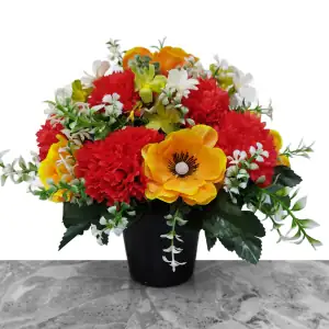 Artificial orange/yellow anemones, red carnations, and white & green cosmos, with gyp and greenery in a full black plastic grave flower pot.