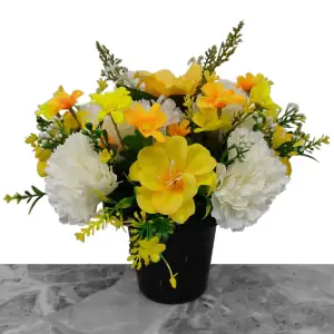 Artificial yellow anemones, cream carnations, and orange & yellow cosmos, with gyp and greenery in a full black plastic grave flower pot.